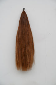 Extensión de cola tono Light Chestnut sobre fondo blanco